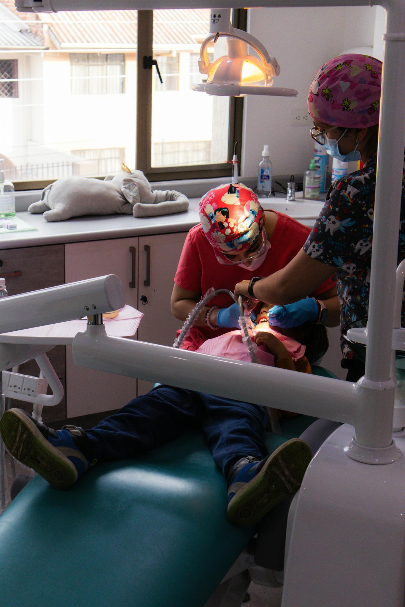 Child receiving dental check-up from professional dentists in a clinic setting.