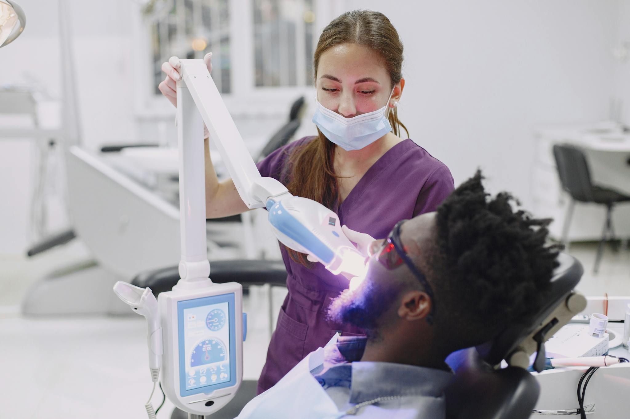 Dental professional using curing light during patient's checkup in a clinic.