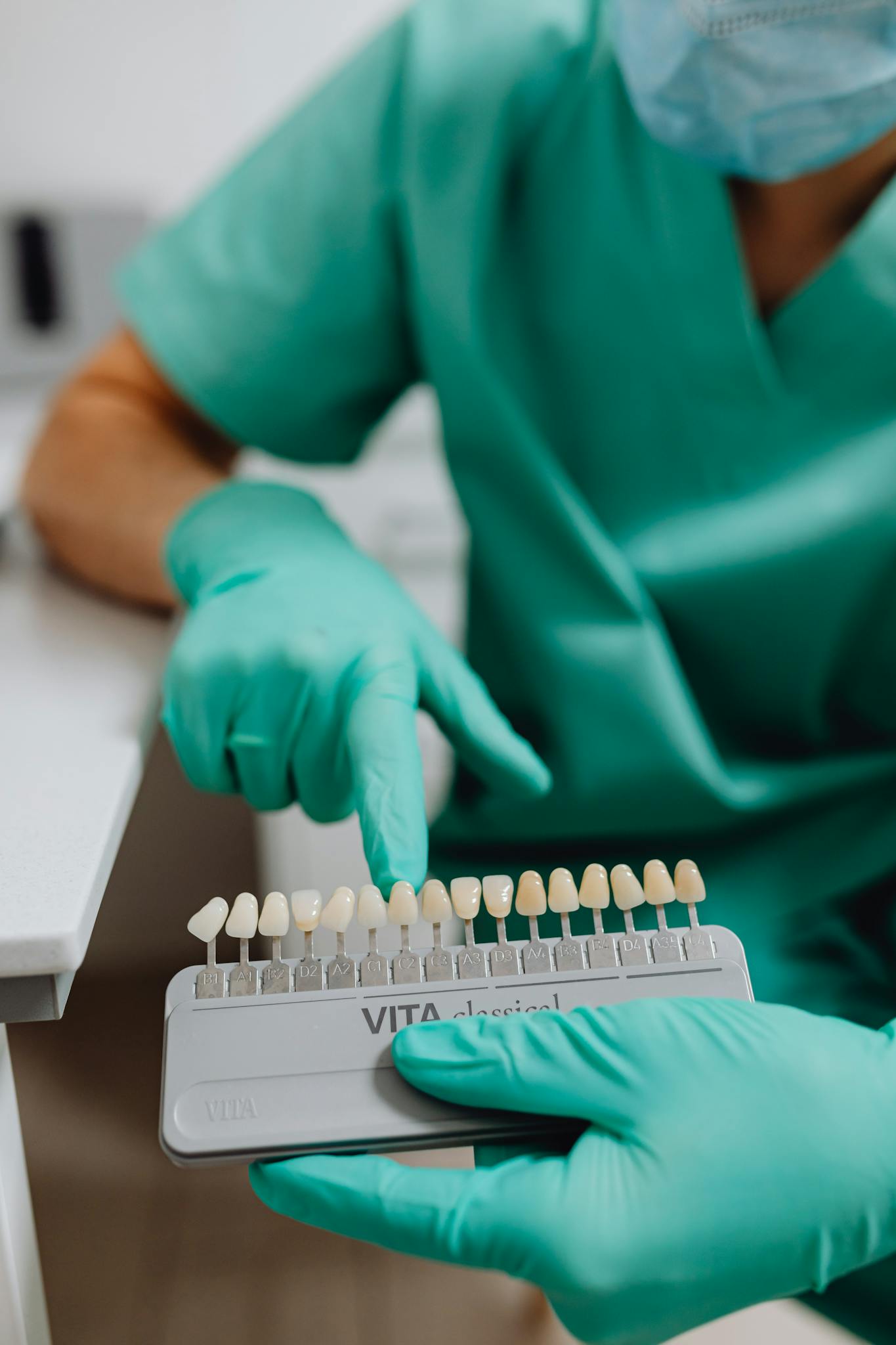 Dental professional using shade guide for teeth color selection in clinic setting.